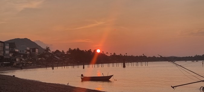 the beach at sunset with a small boat tied near the shore